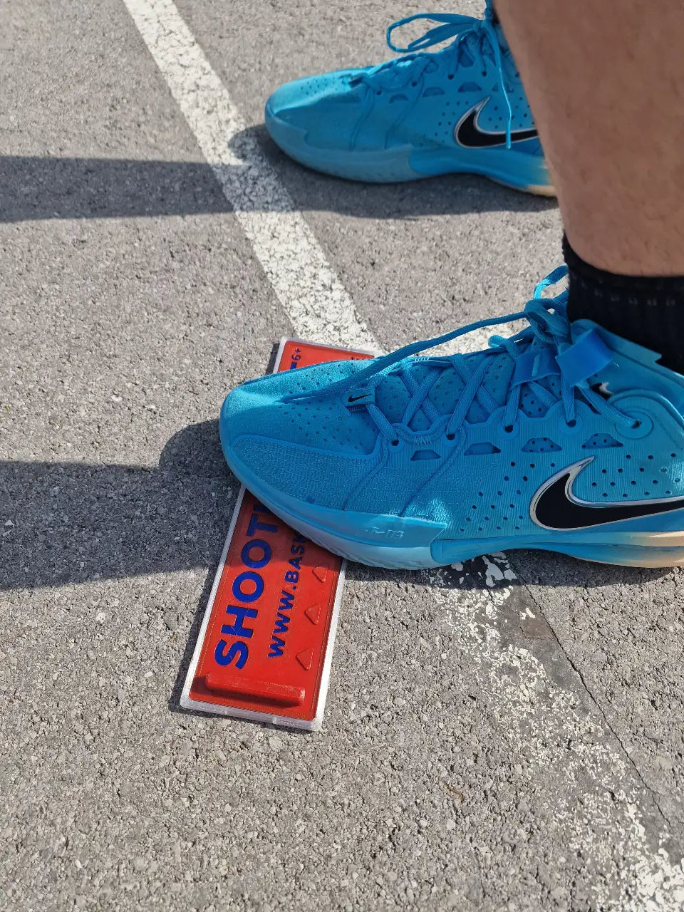 Close-up of a basketball player stepping on the Basketball Witch Shooting Spot Marker with Anti-Slip Case during outdoor basketball play.