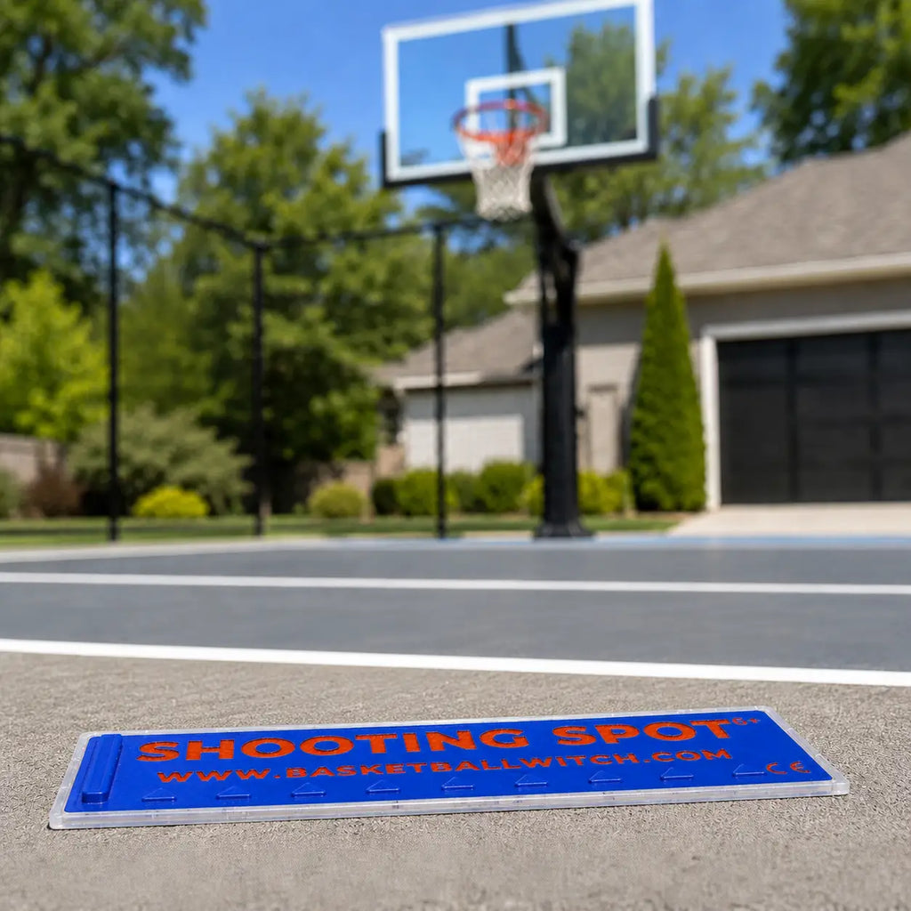 Basketball court with a Shooting Spot marker in the foreground, blurred background of a house and trees.